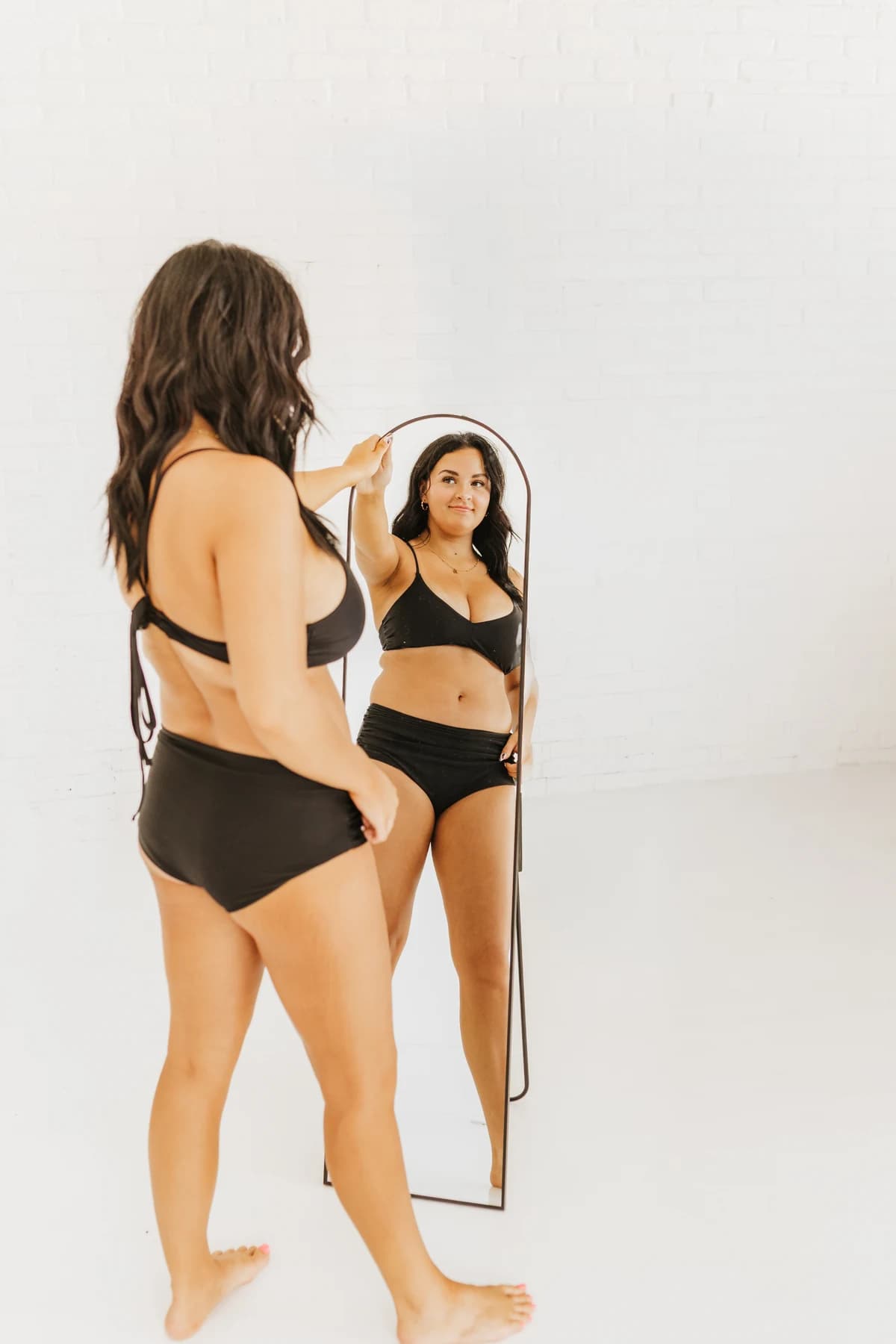 Model looking in a full-length mirror during the SK Glow shoot