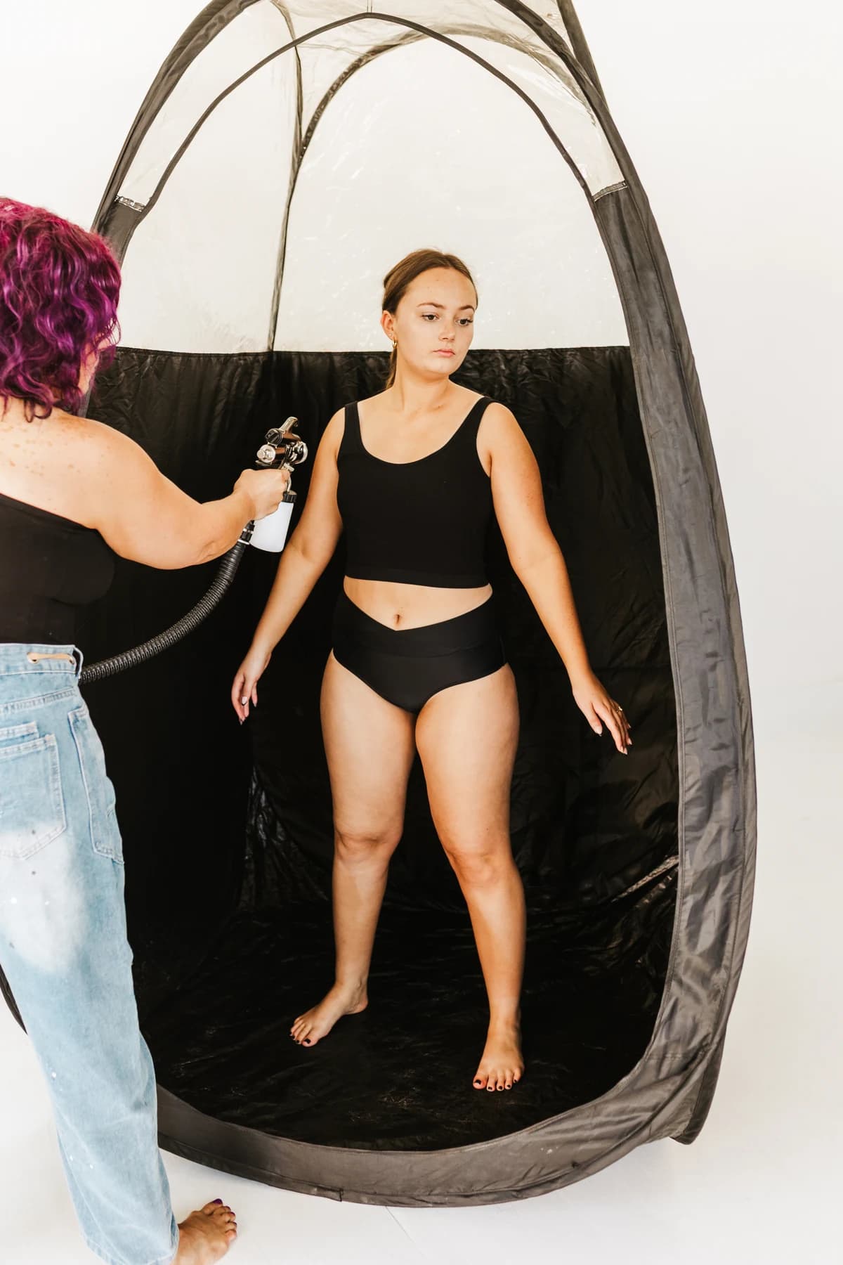 Courtney preparing a spray-tan application with a model