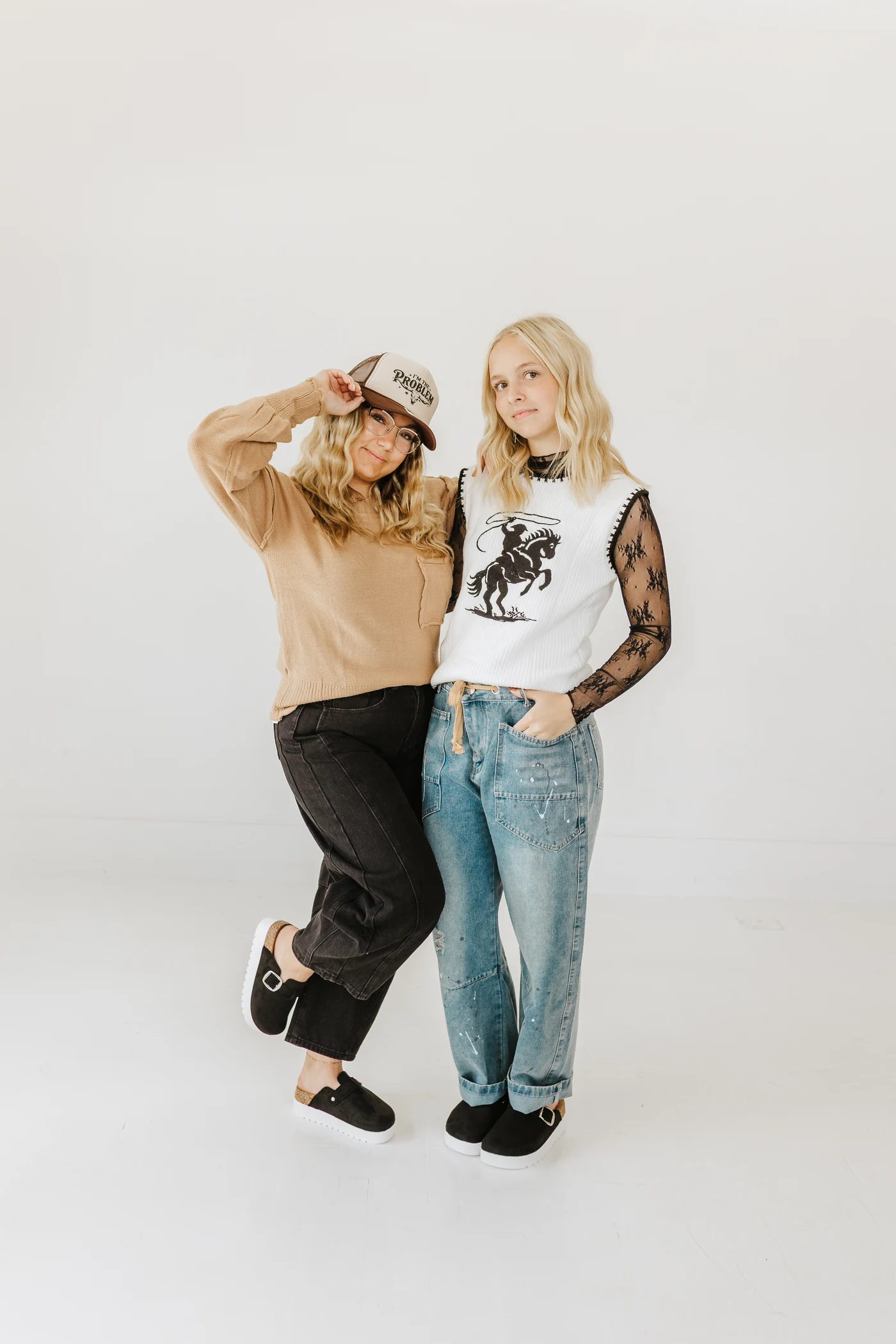 Two friends styling a tan pullover and a western sweater vest with black lace sleeves and denim